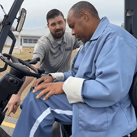 Image of an instructor teaching a prison inmate how to operate a forklift.