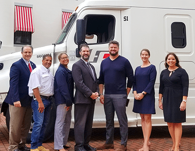 Image of a group of people standing in front of a truck.